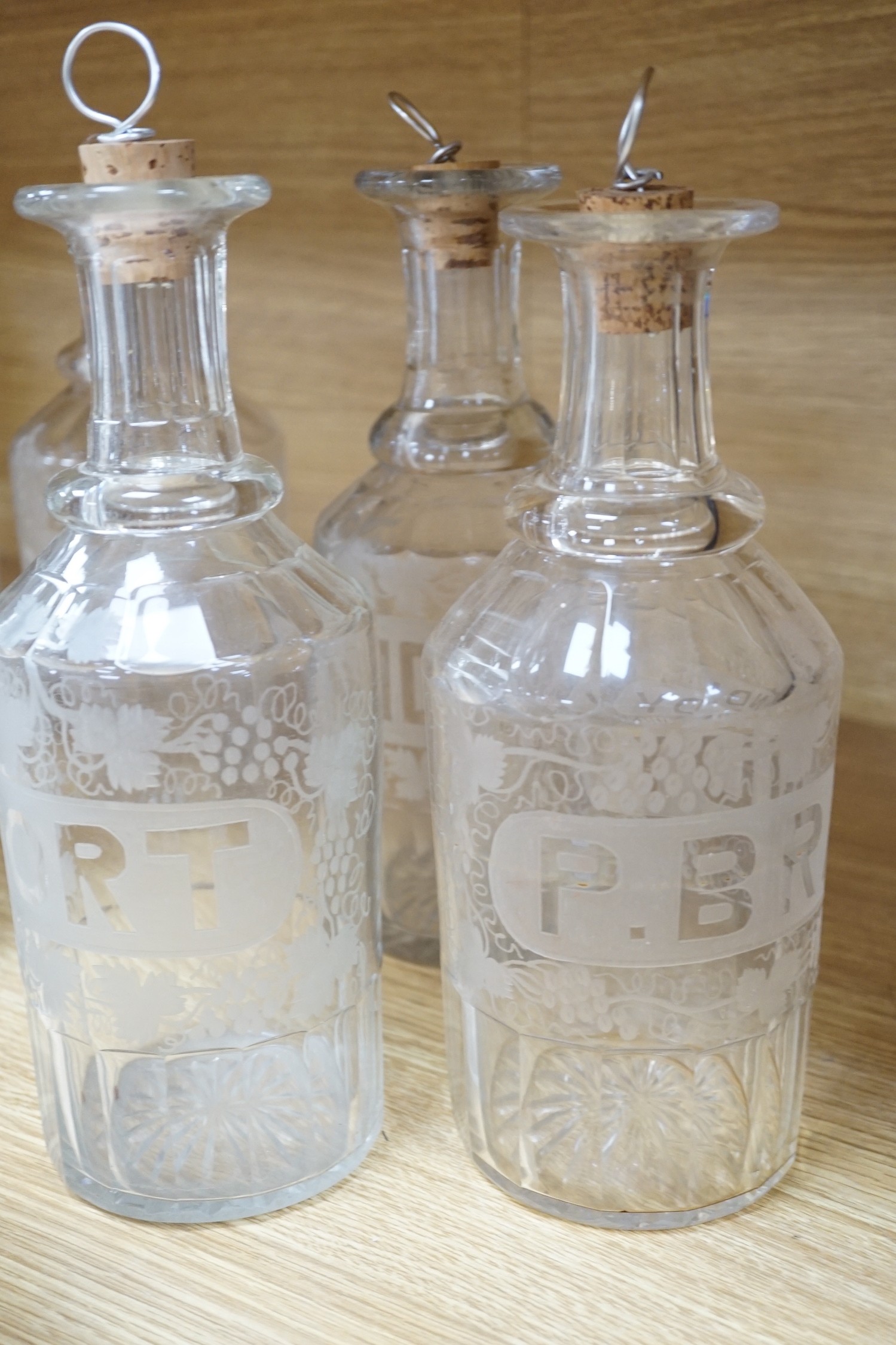 A set of 13 Victorian etched and named glass decanters; 27 cm.